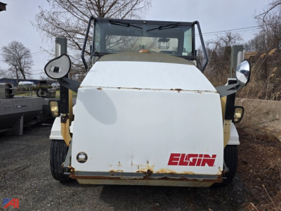 Elgin street sweeper front view showing white body with Elgin logo and rust marks at lower edge.