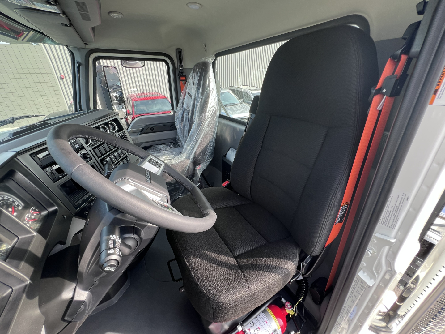 Truck cab interior showing steering wheel and driver seat of a 2026 Mack PI64T conventional daycab.