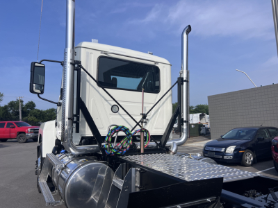 Mack PI64T conventional daycab truck cab and fuel/tank area with chrome exhaust stacks and diamond plate deck