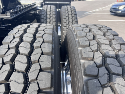 Mack PI64T truck wheel area showing dual rear axles with heavy-duty off-road tread tires and chrome wheel rims.