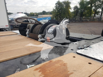 Trailer winch and cable reel on flatbed trailer with wooden deck sections and metal diamond plate, 5/8 inch hook and steel fittings visible.