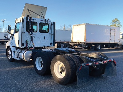 Freightliner Cascadia126 truck tractor (cab and chassis) showing rear dual axles and fifth wheel, with a box trailer in background.