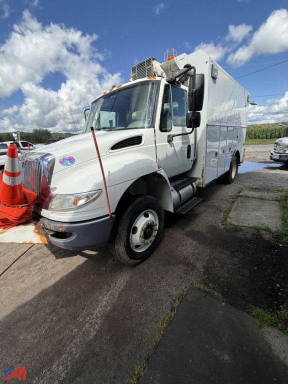 Service body truck showing International 4300 with utility box, side steps, and front wheel; decals on door and equipment mounted on top.