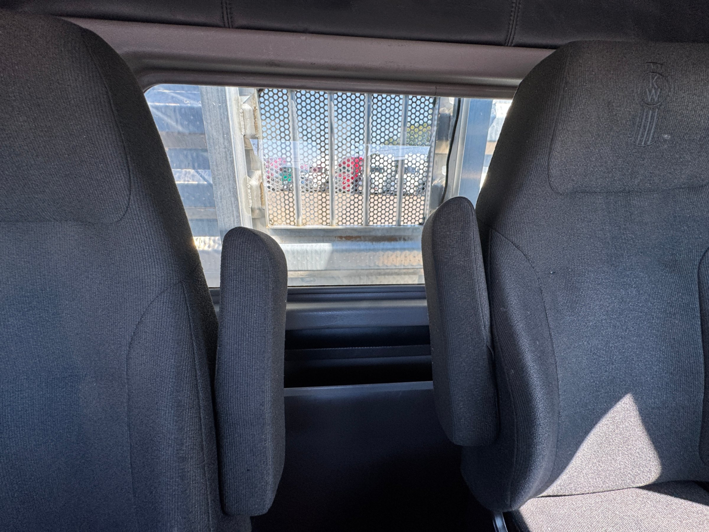 Kenworth W900L interior view showing two front seats and cabin window.