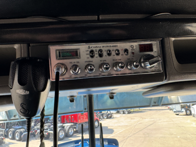 Kenworth W900L interior dash area showing CB radio microphone and control panel with knobs and switches.