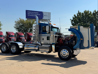 Kenworth W900L conventional daycab shown in side view with exposed engine and chrome fuel tanks.