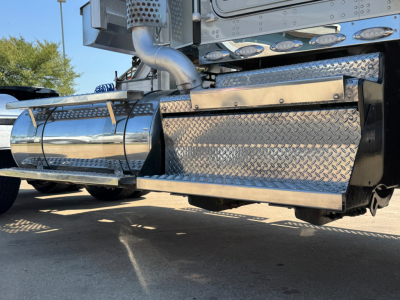 Kenworth W900L truck exhaust and diamond plate side box showing polished chrome fuel tank and undercarriage components.