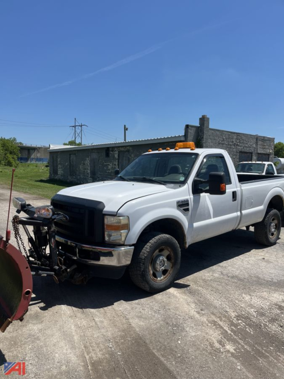 Ford F-350 Super Duty crew cab pickup with plow attachment front view showing white exterior, orange clearance lights, and side mirrors.