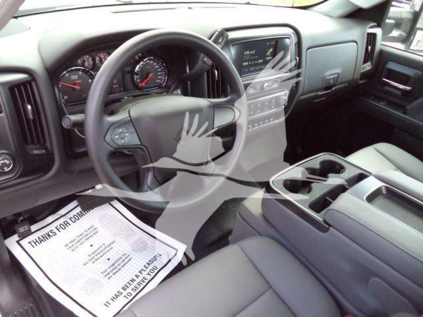 Interior of a 2023 International CV truck cab showing steering wheel, dashboard gauges, center console, and driver-side door; stock number J41633 visible on paperwork on floor.