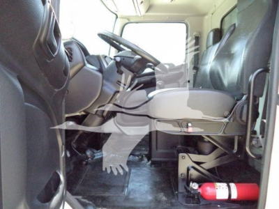 Truck cabin interior of a 2019 Hino 268A, driver seat, steering wheel, and dashboard visible with a red fire extinguisher mounted near the cab floor.