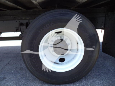 Wheel and tire on a Hino 268A refrigerated truck showing steel white wheel and tire with hub cover and wheel bolts.