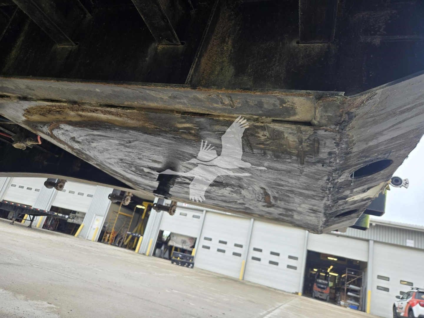 Flatbed trailer underside view showing the black chassis and worn deck edge. Visible are the lower hull and paint wear along the bottom edge.