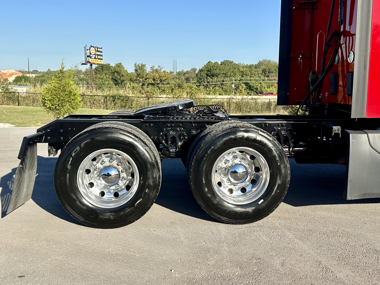 Kenworth T680 chassis showing dual rear wheels and part of the cab with red exterior and chrome wheels.