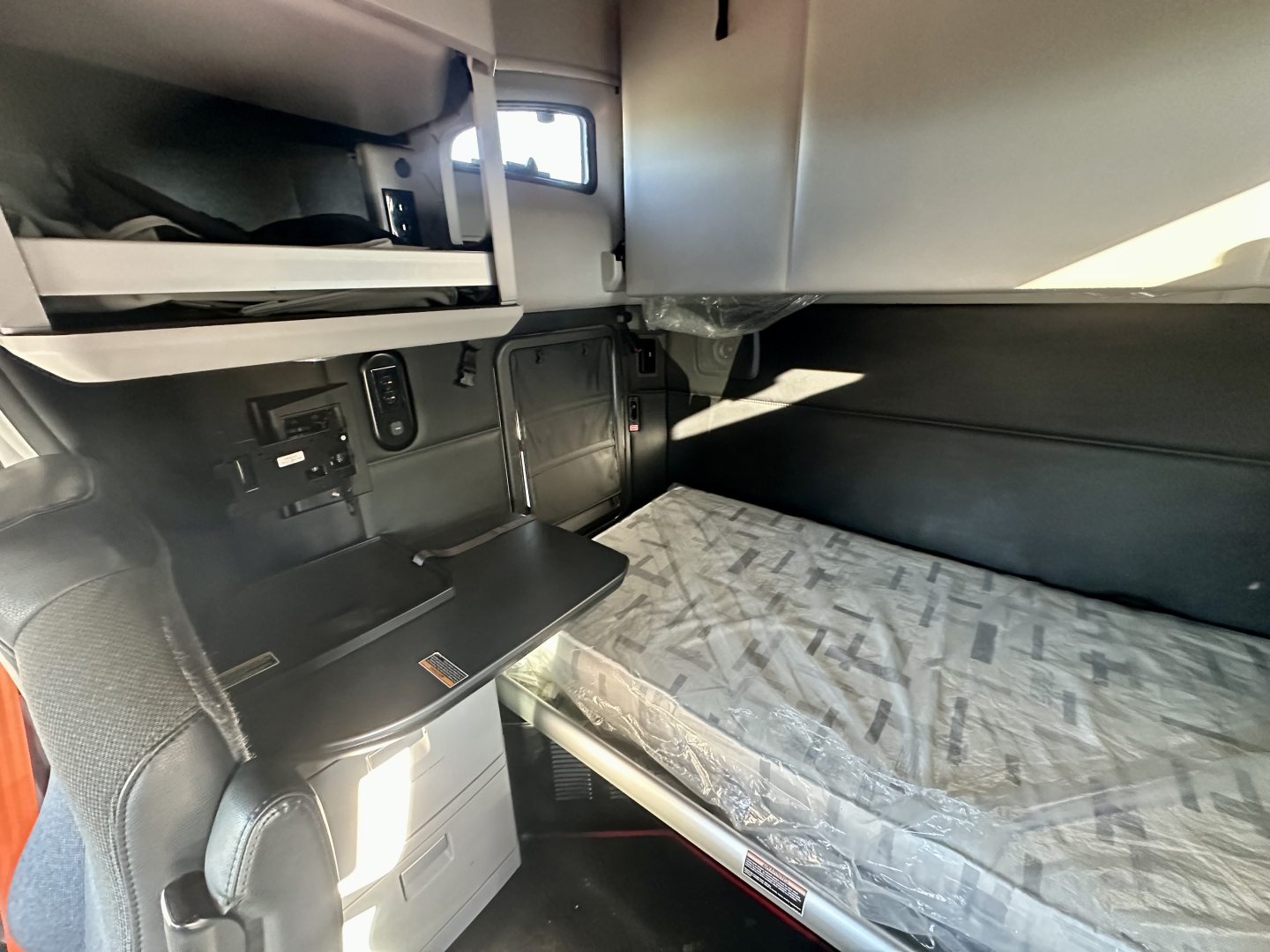 Kenworth T680 interior cab bunk area with bed and storage compartments visible.