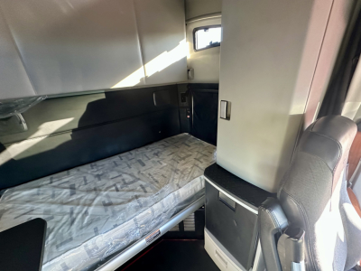 Truck cab bunk area with bed, storage cabinets, and seating; interior cabin view of a Kenworth truck.