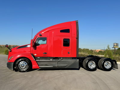 Kenworth T680 conventional sleeper truck side view showing red cab and triple rear axles