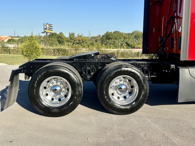Kenworth T680 chassis showing dual rear wheels and part of the cab with red exterior and chrome wheels.