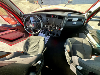 Interior of a 2023 Kenworth T680 cabin showing steering wheel, dashboard, and two front seats