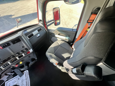 Truck cab interior of a Kenworth T680 showing driver seat, steering wheel, and dashboard with various controls and gear selector.