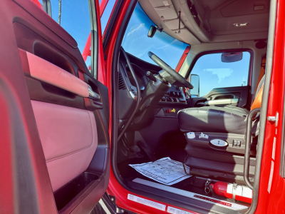 Kenworth T680 truck interior cabin view from driver side door showing steering wheel dashboard and seats.