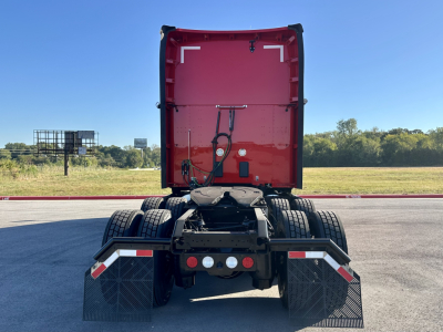 Kenworth T680 rear view showing sleeper cab, dual rear wheels, mud flaps, and rear hitch with red cab back.