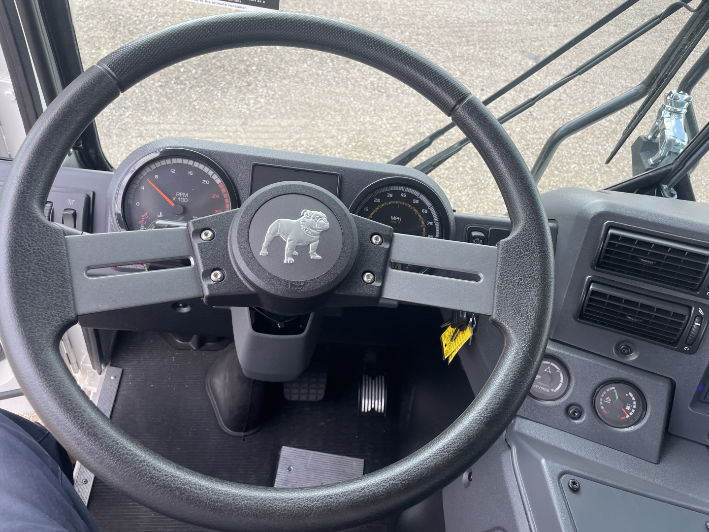 Steering wheel and instrument cluster of a Mack TE64 truck cab interior, with gauges and dashboard controls visible.