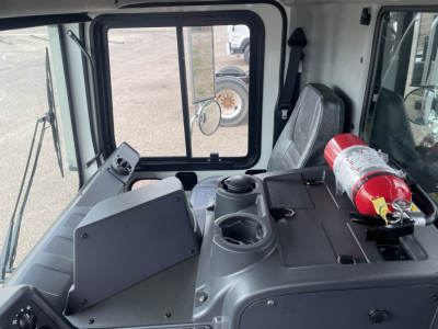 Cab interior of a 2026 Mack TE64 showing dashboard area with cup holders and a mounted fire extinguisher on the right.