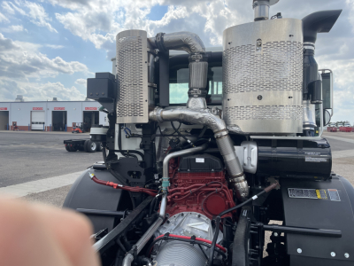 Mack TE64 engine bay showing large turbocharged diesel engine with red block, silver exhaust manifolds, and various hoses.