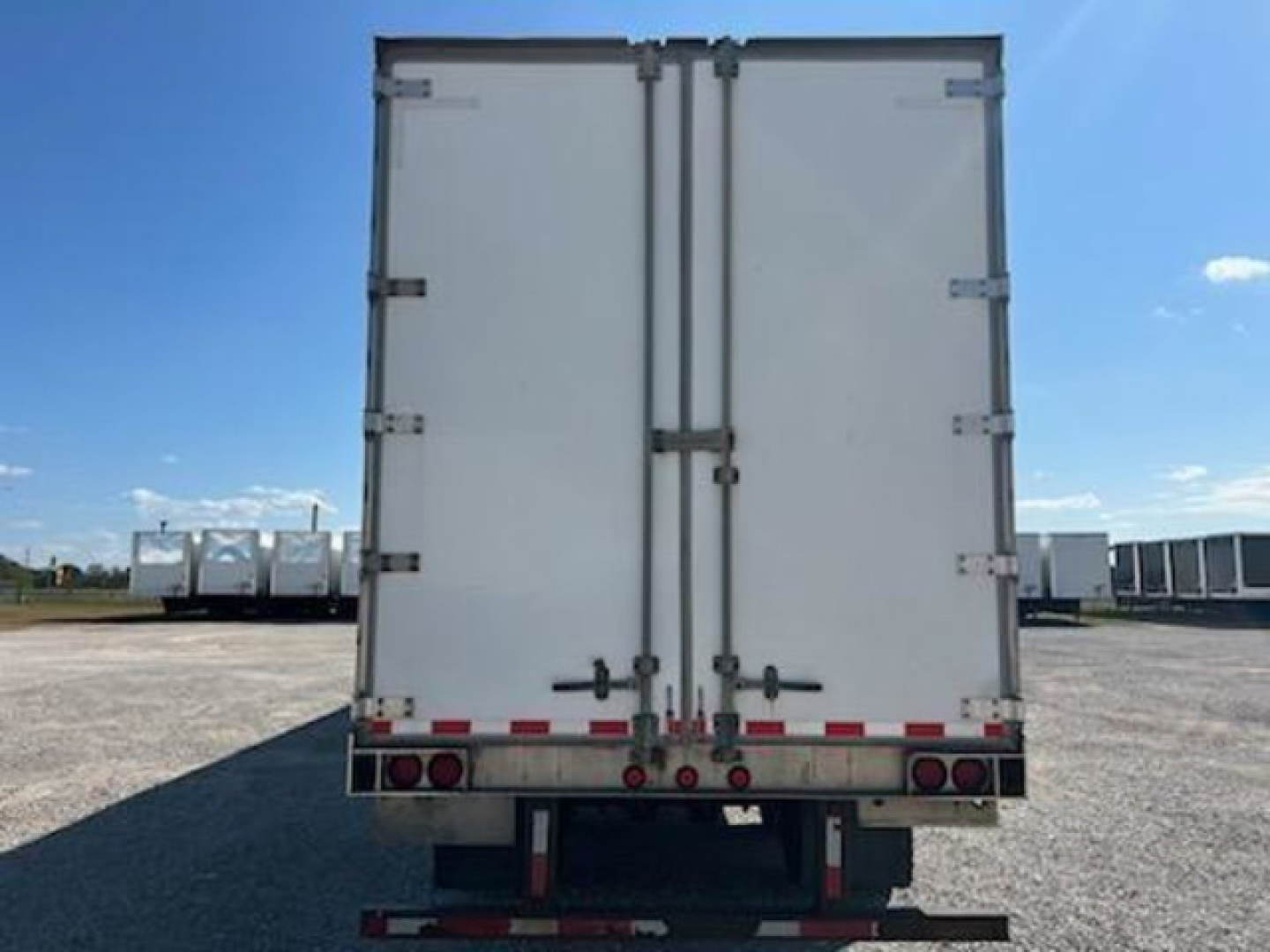 Rear view of a white trailer van with double doors and rear lights.