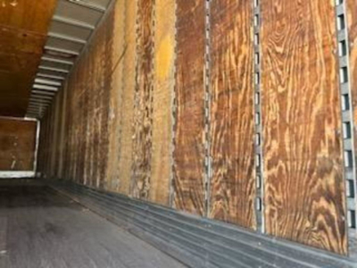 Van trailer interior showing wooden side panels and metal support rails.