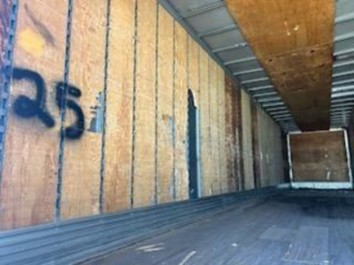 Trailer interior showing wooden wall panels and metal ceiling with a loading at the far end.