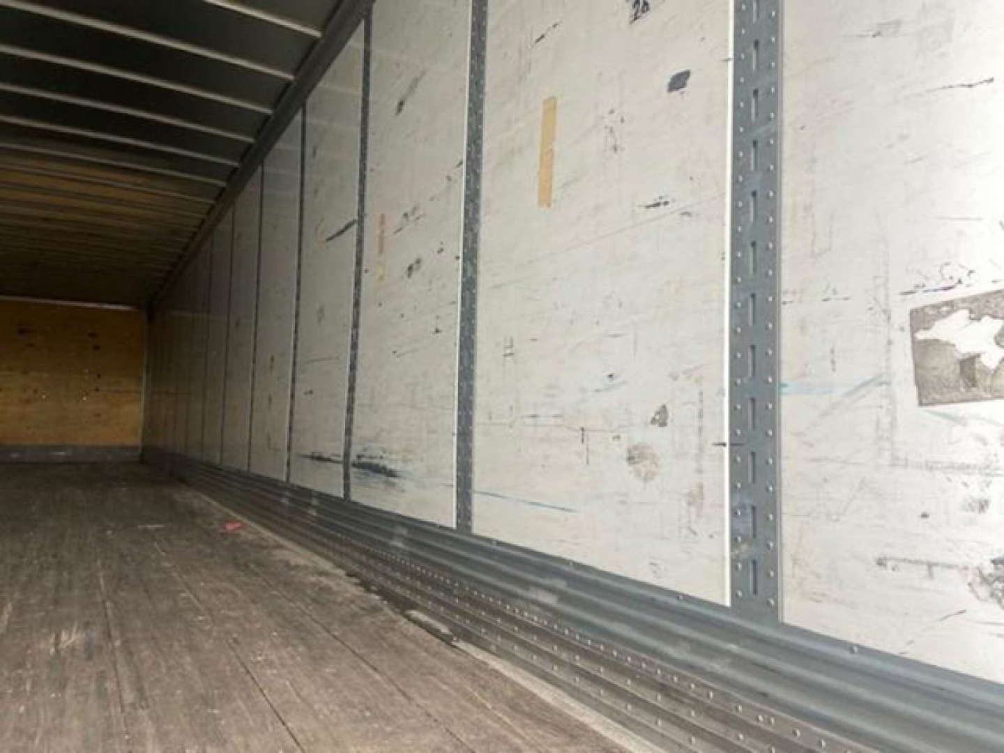 Trailer interior showing wood floor and side wall panels with vertical rails and lashing channels.