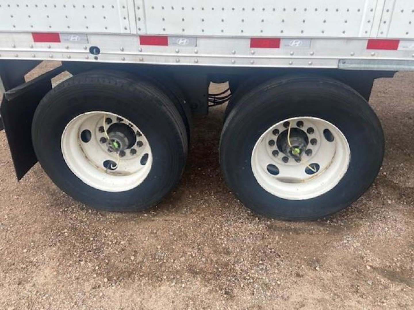 Hyundai van trailer wheels showing dual rear axles and white rims under a silver trailer side wall with red/white reflective strips.