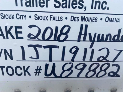 Sign with handwritten vehicle details: VIN partial '3H3V532C1JT191127', stock number 'U89882', '2018 Hyundai' written, and geographic dealership names (Sioux City, Sioux Falls, Des Moines, Omaha) in the background.