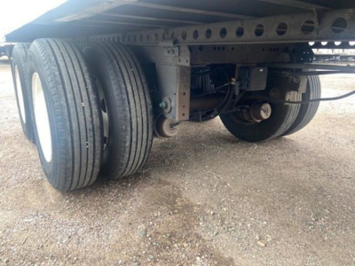 Dual rear wheels and undercarriage of a trailer showing tandem axle setup and suspension components.