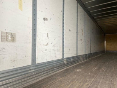 Trailer interior showing empty cargo area with white side panels and metal rails, wooden floor, and cargo trailer walls.