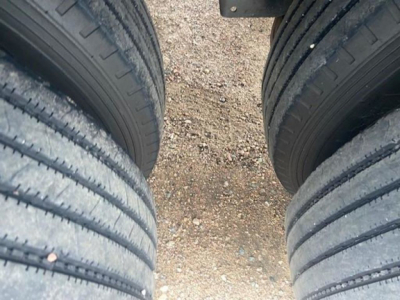 Tandem axle trailer tires and gravel ground viewed from between wheels.