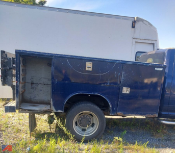 Side view of a blue Dodge Ram 4500 chassis cab with a white utility box, showing storage and compartments along the truck bed.