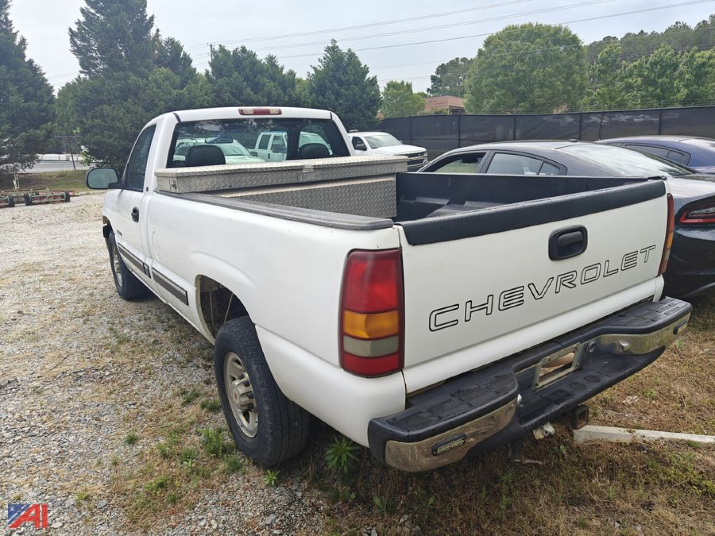 Chevrolet Silverado 2500 pickup truck rear/side view showing bed, tailgate with CHEVROLET emblem, white paint, and diamond-plate toolbox in bed.