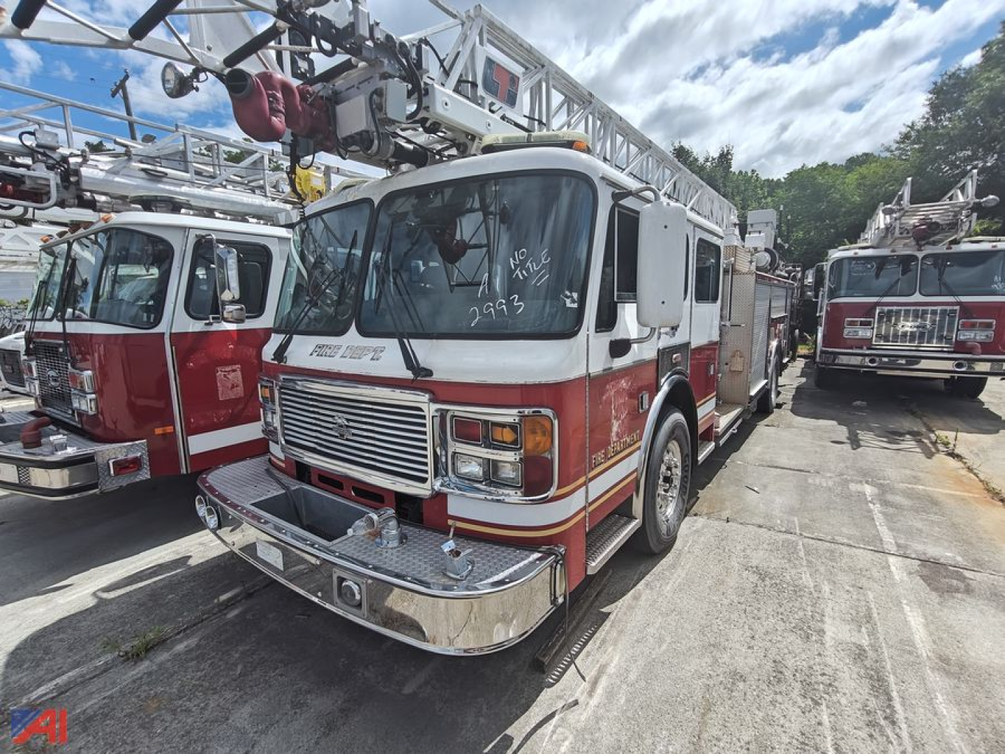 Fire engine in-service ladder truck with chrome front bumper and white cab, red lower body, ladder apparatus on top, other fire trucks in background.