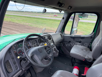 Truck interior showing steering wheel, dashboard, and passenger seat in Freightliner Bearcat asphalt truck cab. Visible gauges, controls, and gray seats.