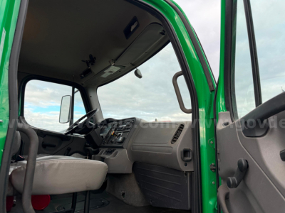 Truck cab interior of a green Freightliner Bearcat Asphalt truck showing steering wheel, dashboard, and driver seat; open door view