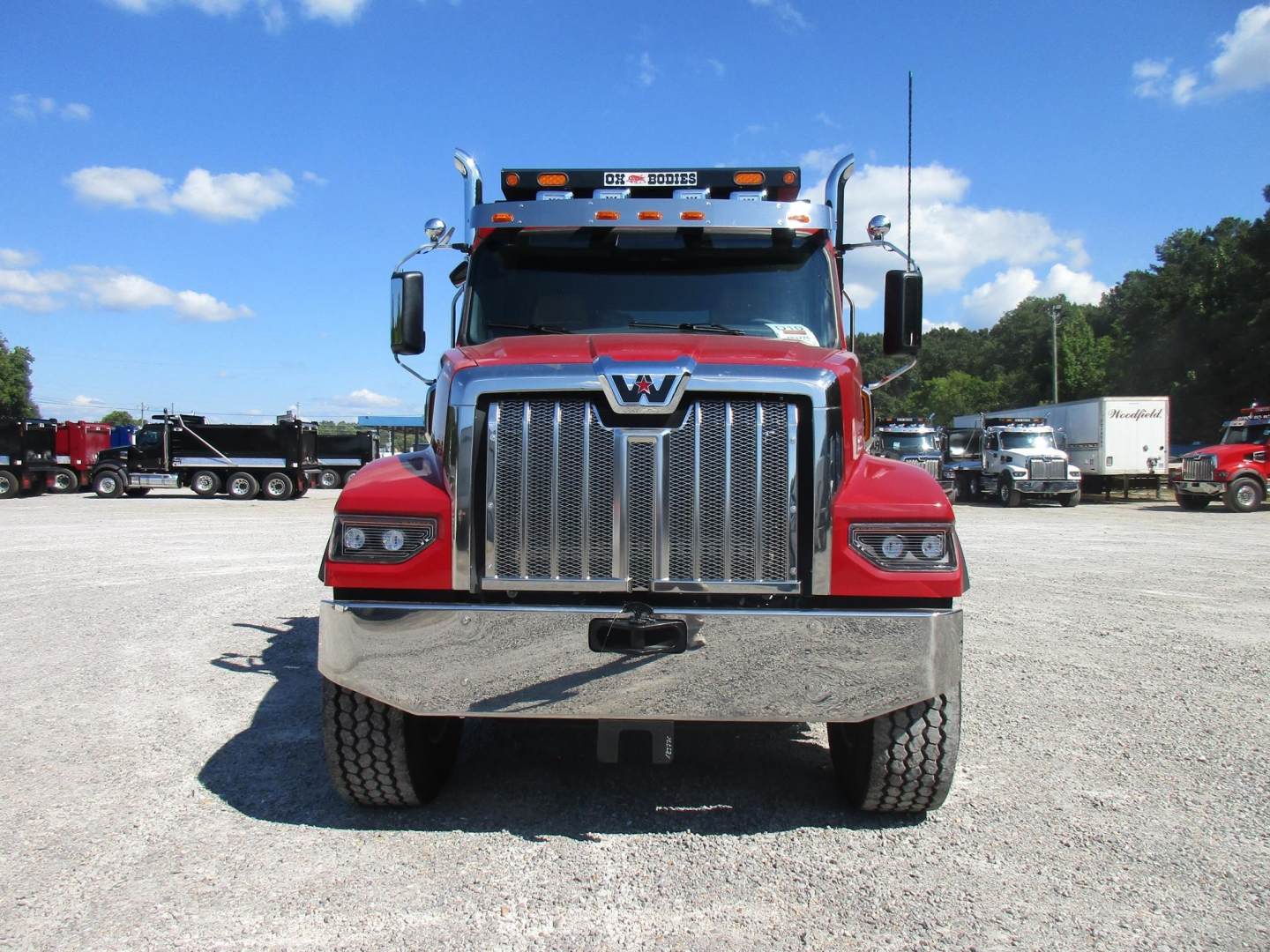 Front view of a red 2027 Western Star 49X dump truck showing large chrome grille, bumper, and dual headlights.
