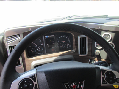 Truck dash view from the steering wheel of a new Western Star 49X showing instrument cluster, steering controls, and dashboard vents.