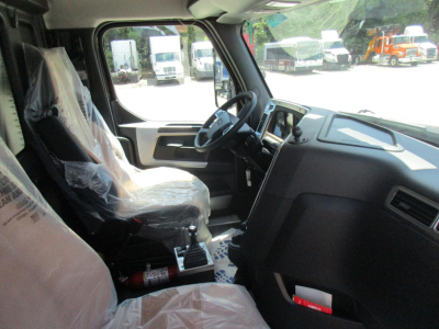 Truck cab interior of a new Western Star 49X showing steering wheel, dashboard, seating wrapped in plastic, and gear shifter.