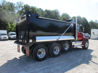 Western Star 49X dump truck in side-rear view showing black dump body with blue stripe and red cab, triple rear axles, chrome wheels.