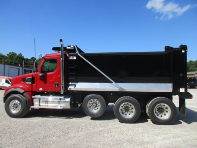 Red Western Star dump truck with black dump bed, side view. Text on cab and chrome exhaust stack visible.