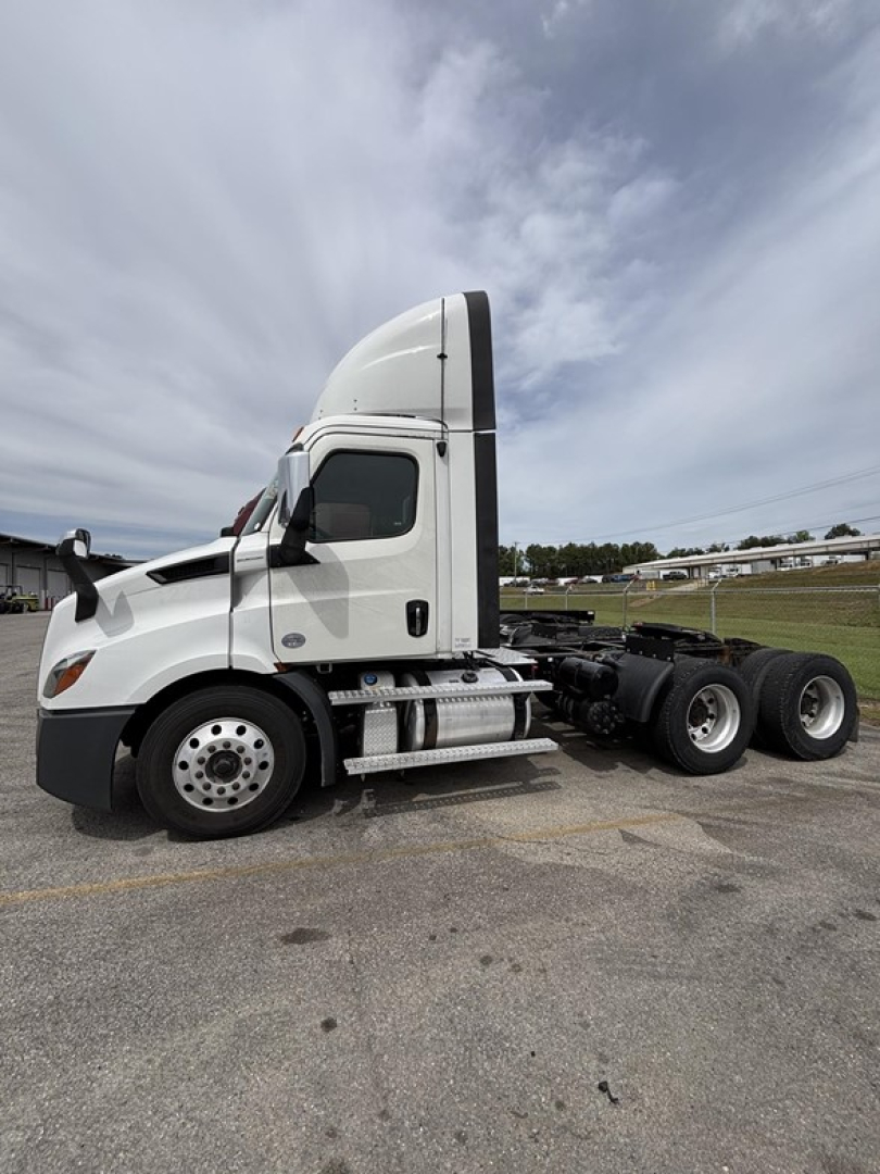 Semi truck side view showing Freightliner Cascadia 116 sleeper cab, with front twin exhaust and chrome fuel tanks; no visible text on exterior