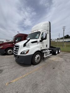 Cabover view of a 2020 Freightliner Cascadia 116 day cab tractor showing front and side, white with sleeper roof, without trailer.