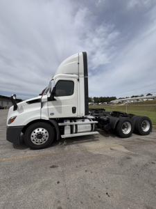 Semi truck side view showing Freightliner Cascadia 116 sleeper cab, with front twin exhaust and chrome fuel tanks; no visible text on exterior